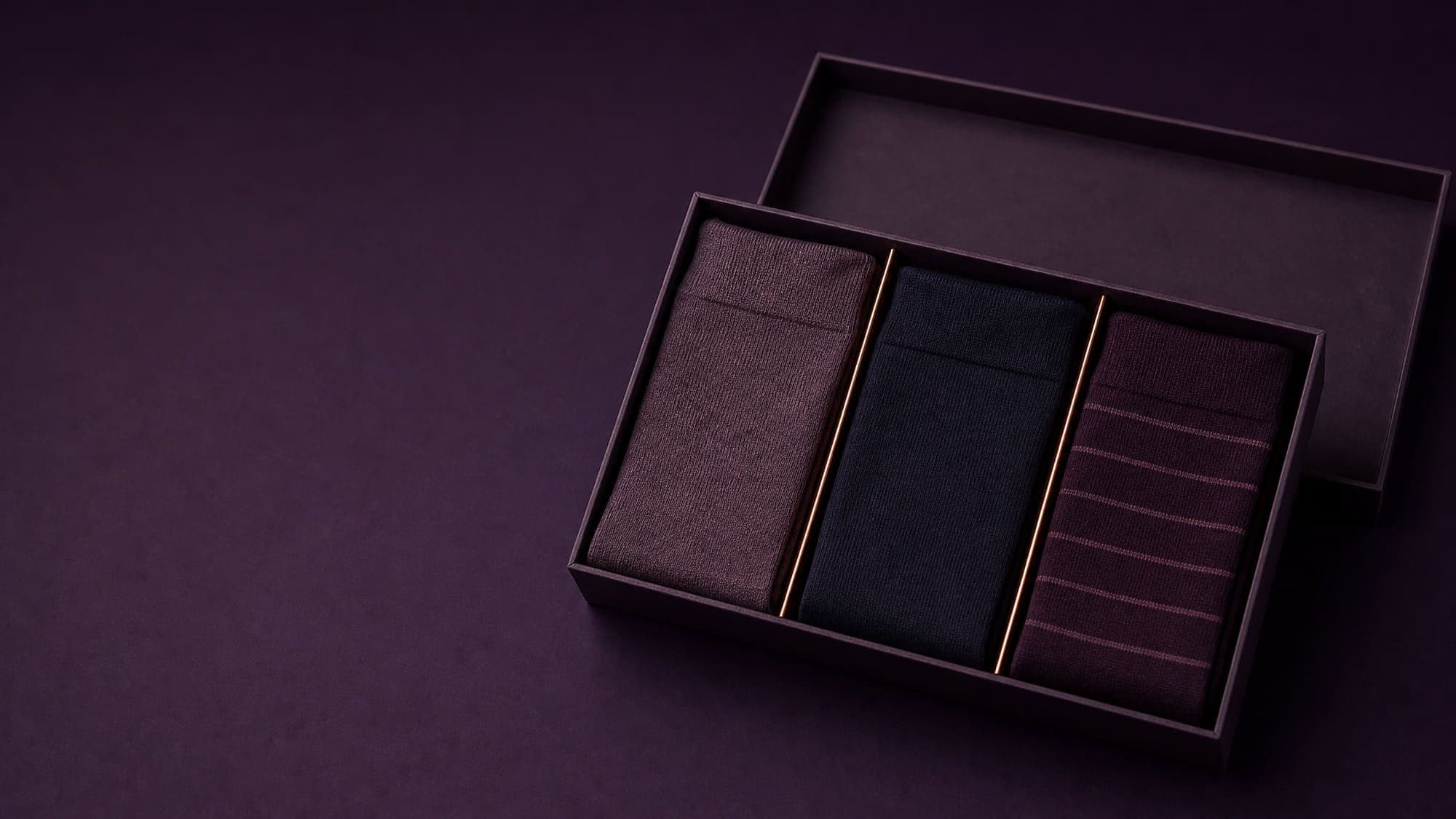 An open gift box with three pairs of folded socks in three separate compartments